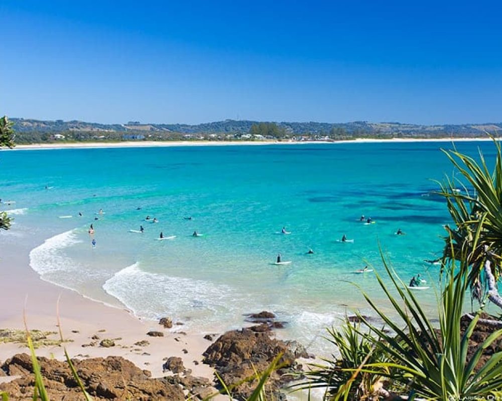 alot of surfers are at the shore of byron bay clear waters